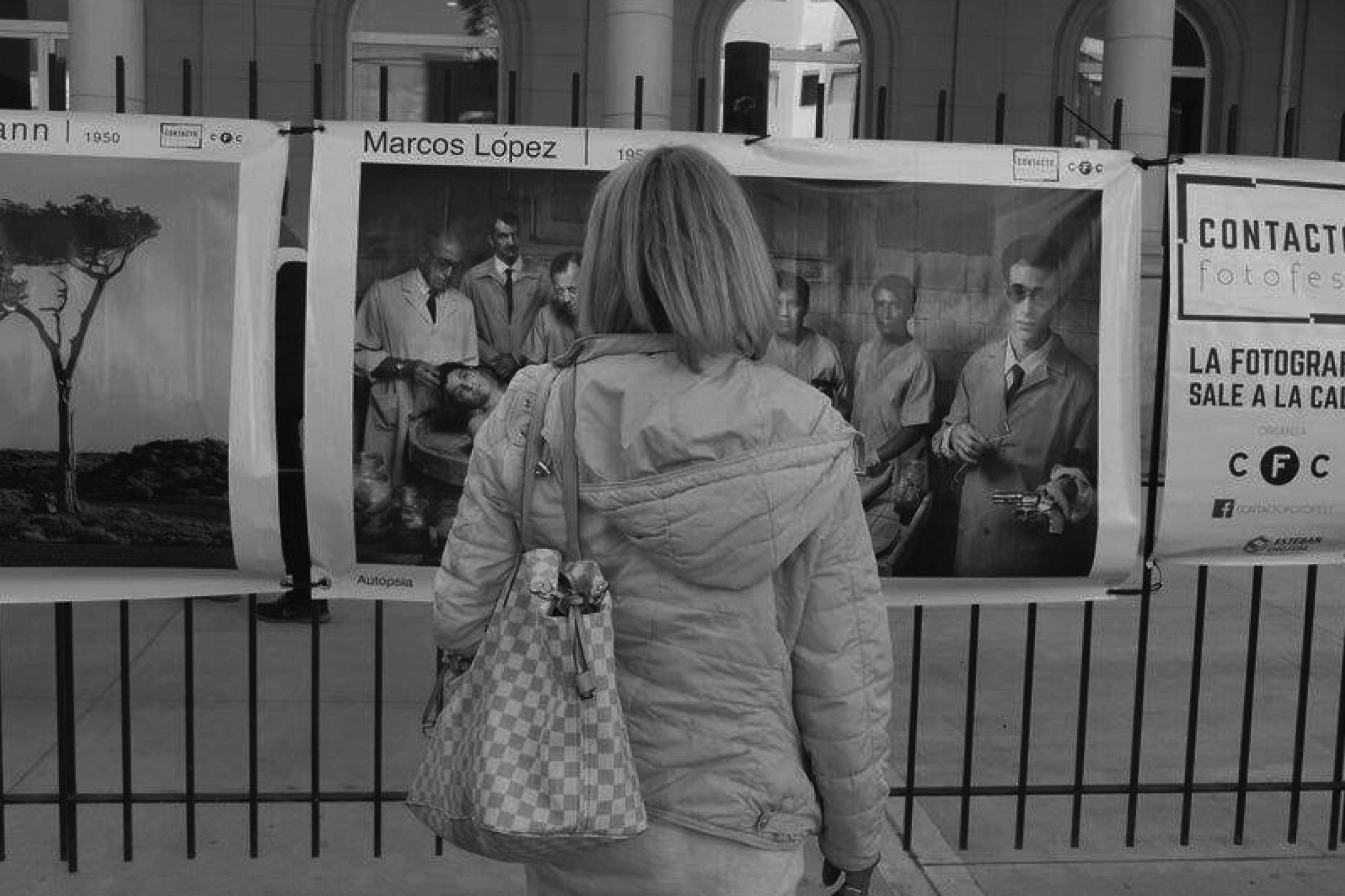 Una mujer recorre las fotografías que el colectivo exhibió sobre las rejas de una casa en Mar del Plata